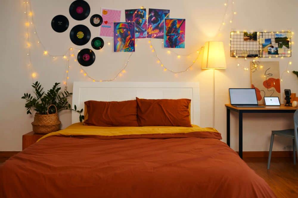 Una habitación juvenil decorada con discos de vinilo, pósters, fotografías y luces cálidas. Los elementos en la pared reflejan la personalidad del ocupante y convierten el espacio en un lugar único y acogedor.