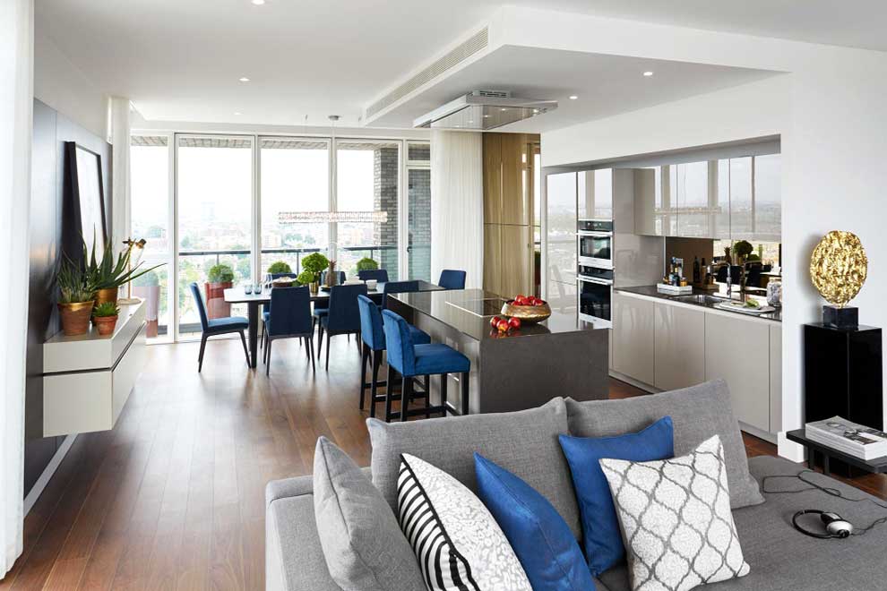 La imagen muestra un elegante comedor integrado con la sala en un espacio de concepto abierto. Los tonos neutros, las sillas tapizadas, la iluminación decorativa y los detalles modernos crean un ambiente sofisticado, amplio y acogedor.