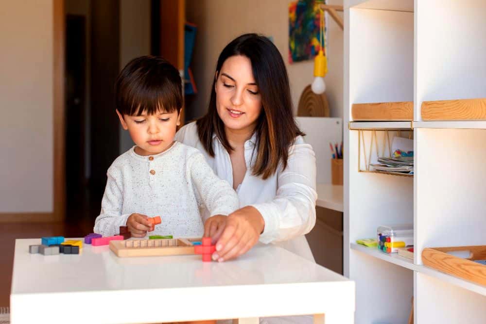 Una madre y su hijo acomodan piezas de juego en una mesa, fomentando hábitos de orden y responsabilidad desde temprana edad.