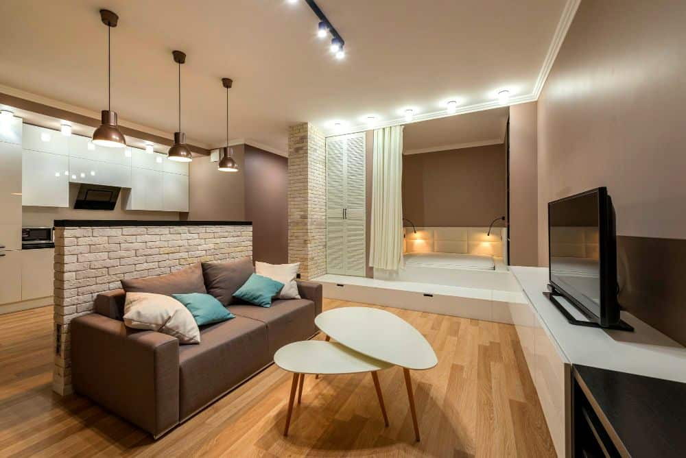 Se observa un departamento de concepto abierto donde sala, cocina y dormitorio comparten un mismo espacio. La distribución inteligente, la iluminación cálida y los tonos neutros crean un ambiente moderno, acogedor y funcional.
