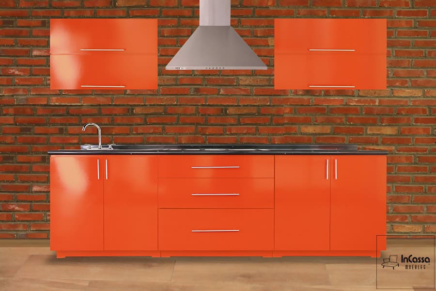 Una toma frontal de la cocina integral para parrilla, la cual se encuentra instalada en una pared de ladrillo. Todos los módulos que conforman la cocina son de color naranja completo, mientras que su cubierta es de formica en estilo mármol negro; cada puerta y cajón cuenta con una jaladera metálica de estilo "T".