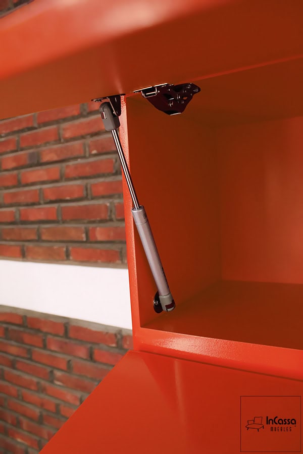 Una toma más cercana de los pistones neumáticos que conforman el sistema de apertura y cierre vertical de las alacenas superiores. La foto además permite apreciar de manera mas cercana el acabado de la pintura naranja presente tanto en el interior como en el exterior del módulo.