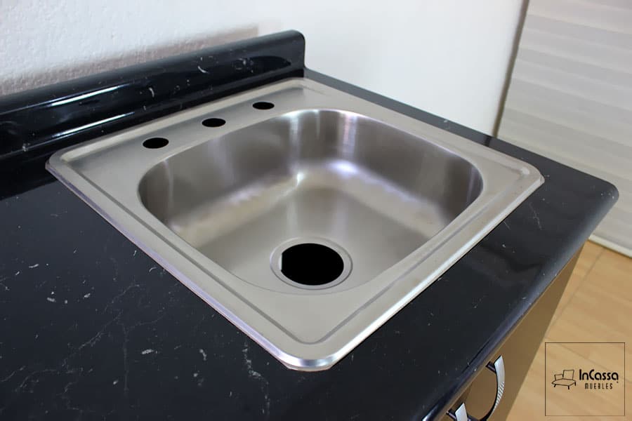 La fotografía permite observar la tarja de acero inoxidable de la Cocina integral AMSTERDAM de 2.10m para ESTUFA en color chocolate con turquesa y cubierta de formaica en estilo mármol negro. El acercamiento resalta la cubierta con acabado tipo mármol, ofreciendo una superficie resistente y funcional para las actividades diarias de la cocina.