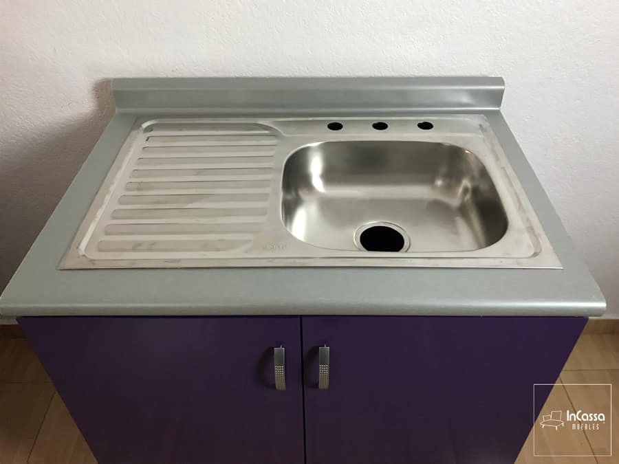 Módulo inferior de la cocina con tarja de acero inoxidable, está es de tina sencilla con escurridor. La foto además ofrece una vista más cercana de la cubierta de formaica de tono aluminio.