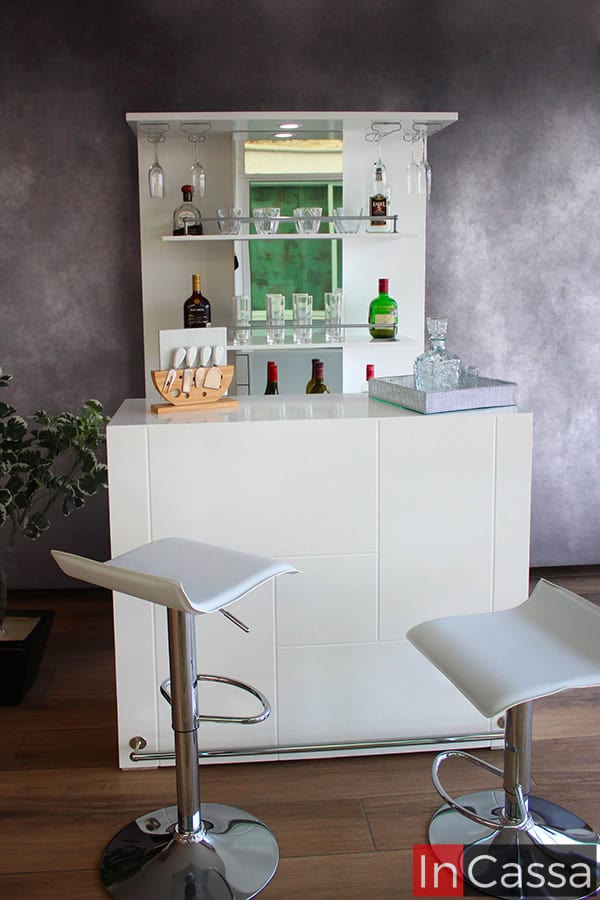 Se muestra la cantina con todos sus componentes desde una toma frontal, permitiendo apreciar el largo de cada uno de sus módulos, los cuales son de color blanco completo. También se presentan los dos bancos blancos incluidos en la cantina, los cuales son ajustables y se muestran en alturas distintas.