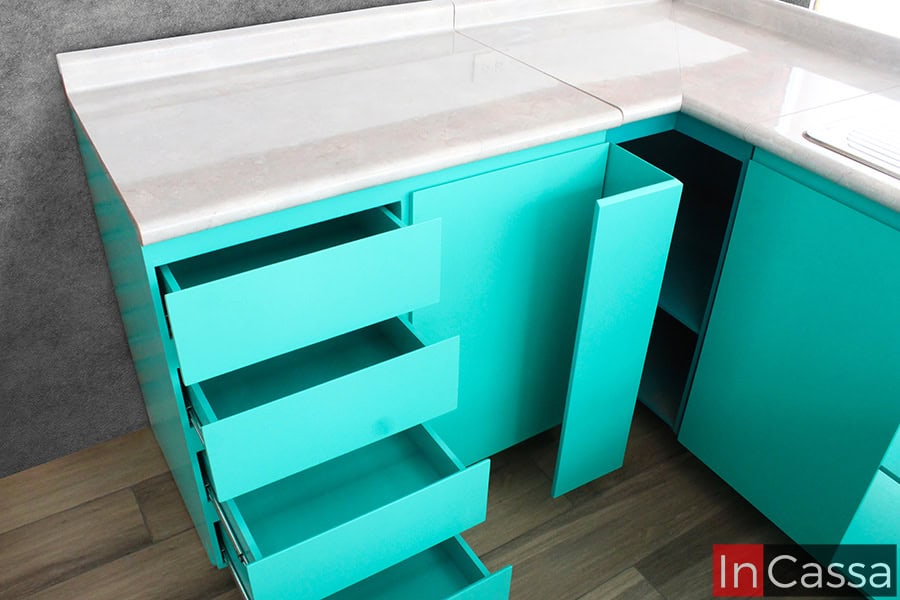 Se presenta un módulo inferior con cuatro cajones amplios y correderas metálicas, acompañado por un modulo esquinero con compartimento ideal para frascos o condimentos. Todo en un vibrante color turquesa con cubierta de formaica en estilo mármol escalona.