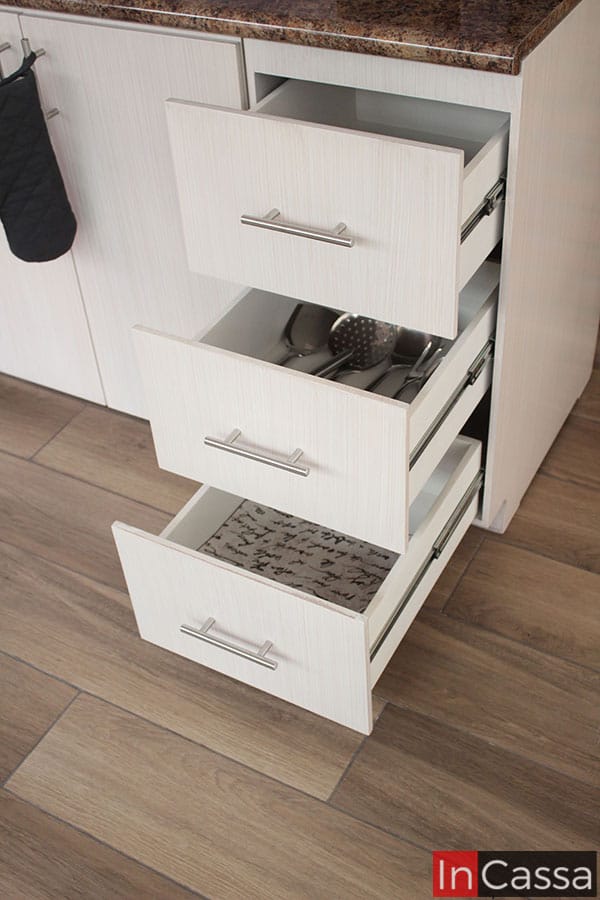 La foto presenta el mueble carnicero con sus tres cajones abiertos, mostrando su estructura completa la cuál es de color blanco con un doble frente con acabado paja. Cada cajón cuenta con un mecanismo de rieles metálicos para su apertura y cierre, además de una jaladera de barra T en su doble frente.