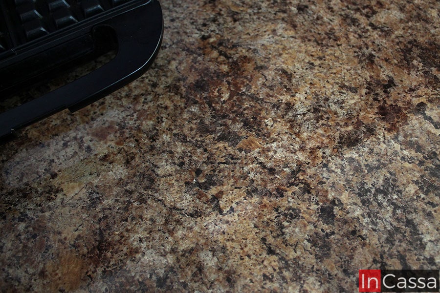 La imagen se enfoca en la cubierta de formaica de los módulos inferiores, dejando apreciar completamente su estilo cuarzo café con acabado brillante.