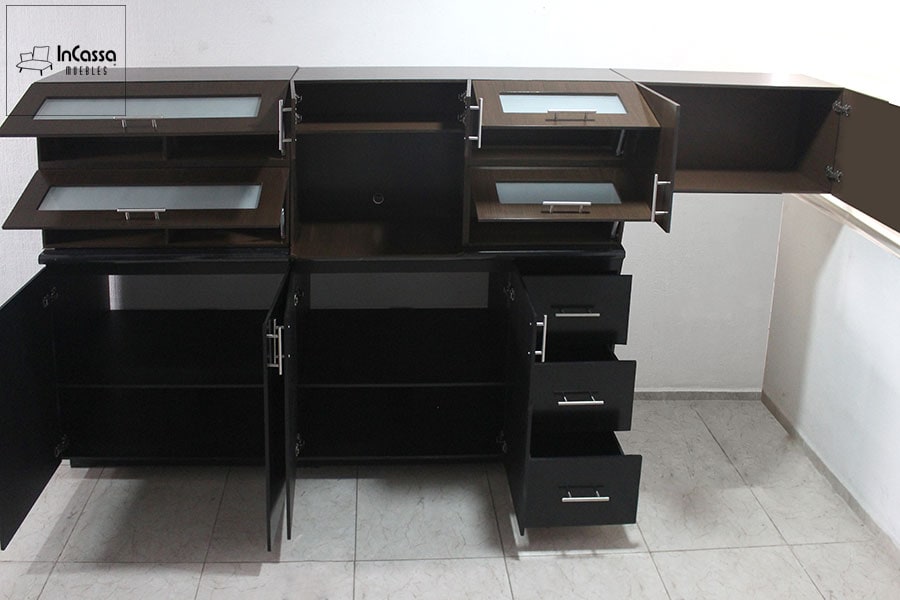 La cocina integral en color chocolate exhibe todos sus compartimentos abiertos, revelando el amplio espacio de almacenamiento. Se aprecian puertas elevables con vidrio esmerilado, alacena central y cajones con correderas metálicas de extensión.