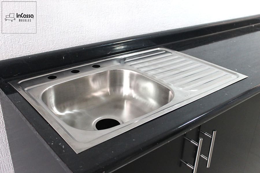 En esta imagen se observa la elegante cubierta de formaica estilo mármol negro con acabado brillante y tarja de acero inoxidable integrada. El mueble en color chocolate aporta un contraste moderno y sofisticado al diseño de la cocina.