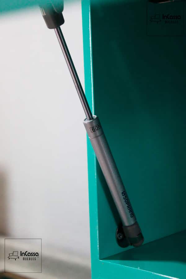 Una toma de los pistones neumáticos instalados en el gabinete superior de la cocina, en vibrante color menta completo. Estos mecanismos aseguran una apertura suave y controlada, añadiendo funcionalidad y seguridad al diseño.