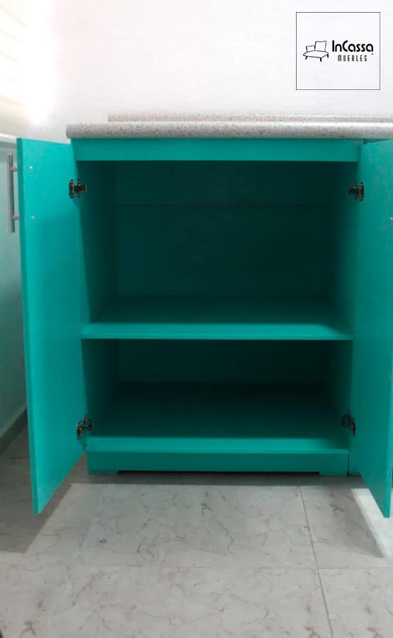 La imagen muestra uno de los gabinetes inferiores de la cocina, diseñado con dos niveles de almacenamiento para maximizar el espacio. Las puertas cuentan con bisagras resistentes que garantizan durabilidad, y la estructura completa del modulo conserva un vibrante color menta.