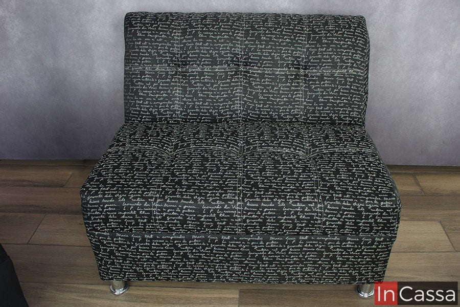 Toma frontal de uno de los love seat tapizado en tela lino Da Vinci negro, en la que podemos ver más a detalle los acabados capitoneados del respaldo y el asiento, así como una mirada un poco más cercana de las patas delanteras que sostienen el mueble, las cuales son metálicas con un acabado cromado.