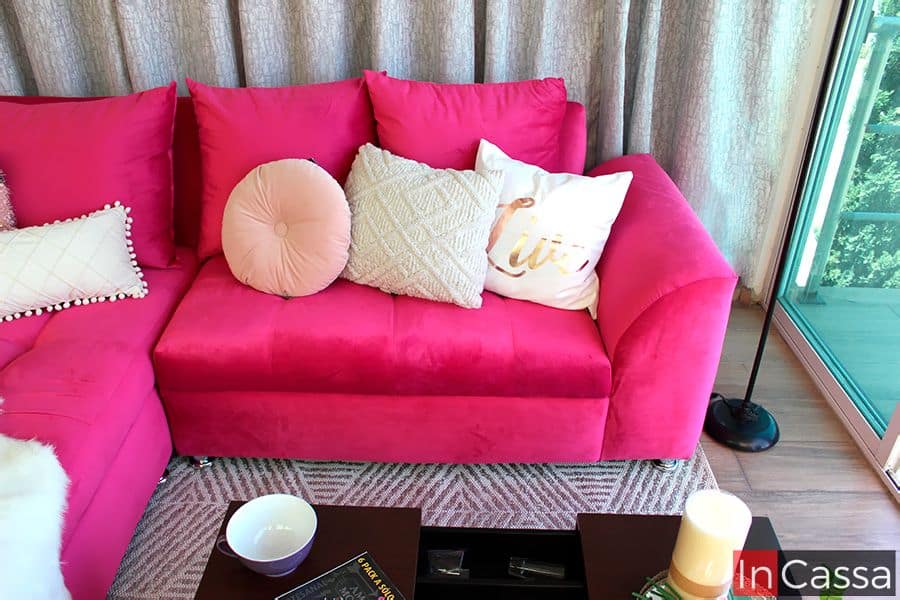 El love seat de la Sala Bangladés luce tapizado en suede fucsia, acompañado de cojines en tonos neutros y rosados que equilibran el diseño. Sus líneas rectas y brazos acolchados aportan comodidad, mientras que el acabado vibrante añade un estilo moderno y atrevido al espacio.