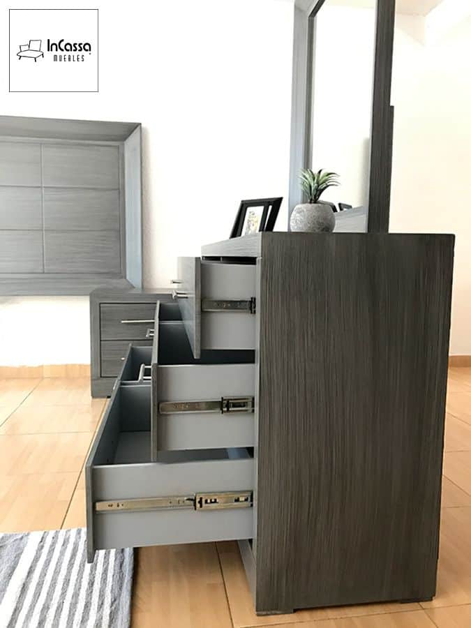 Se observa el lateral del tocador Barcelona en elegante acabado gris cenizo oscuro, con todos sus cajones abiertos mostrando las correderas metálicas. Su estructura robusta y funcional lo convierte en una pieza clave para la recámara.