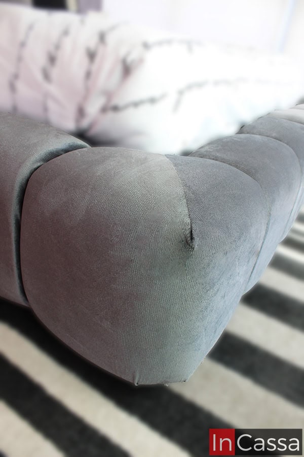 La toma muestra un enfoque lateral de la base, donde se puede observar la suavidad del tapizado suede gris oxford y el acabado acolchonado en los bordes. Este diseño envolvente proporciona una estructura firme y cómoda a la vez