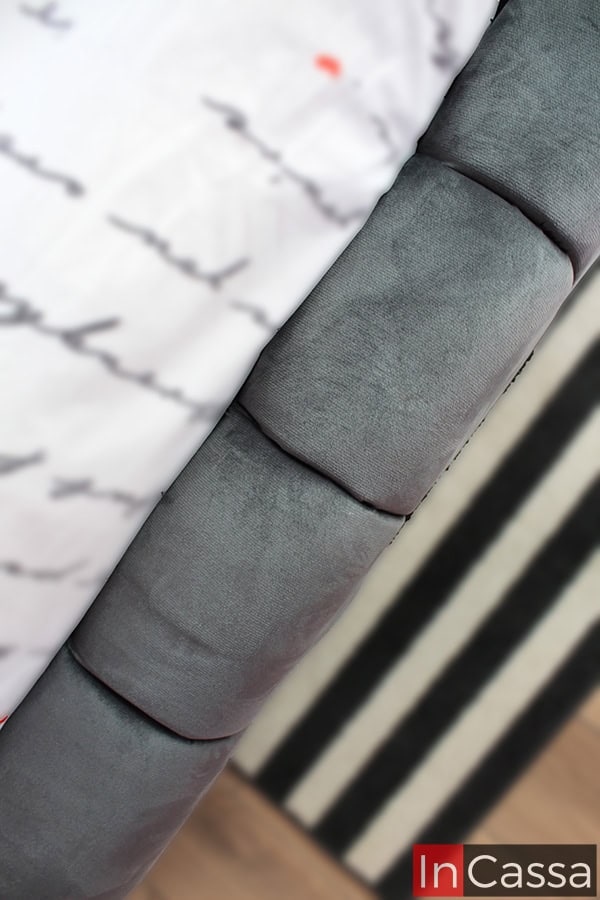 La foto destaca un ángulo superior de la base, donde se pueden notar las costuras cuidadas y el tapizado de suede gris oxford que cubre toda la superficie, ofreciendo un soporte resistente y atractivo.