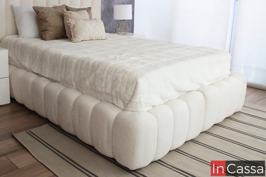 La imagen muestra la Base de Cama Viral Estilo Pinterest modelo SEDONA tapizada en suede hueso, destacando su diseño curvo y voluminoso que aporta una sensación acogedora, elegante y completamente en tendencia para recámaras modernas.
