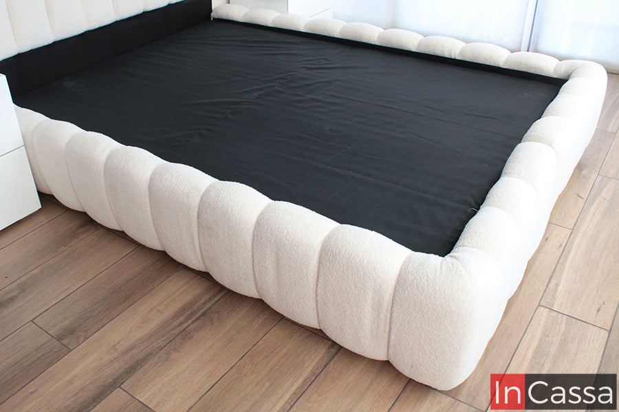 En esta imagen se aprecia la estructura completa de la Base de Cama Viral Estilo Pinterest modelo SEDONA tapizada en suede hueso, resaltando su diseño envolvente con formas curvas acolchadas que brindan un estilo moderno, elegante y acogedor.