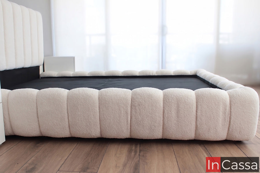 La imagen presenta la Base de Cama Viral Estilo Pinterest modelo SEDONA tapizada en suede hueso, destacando su silueta acolchada tipo nube y acabado suave que transforma cualquier recámara en un espacio moderno, cálido y sofisticado.