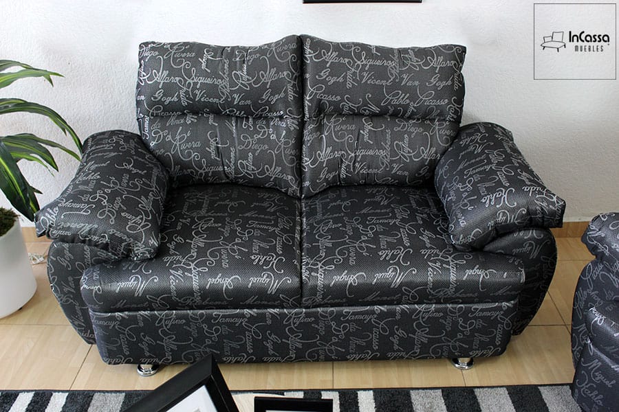 Se presenta el love seat de la Sala Modelo Bora Bora, tapizado en lino artistas color negro con estampado de letras en gris. Su respaldo alto con cojines acolchados y brazos amplios brindan comodidad, mientras que las patas metálicas cromadas aportan un toque moderno y elegante al conjunto.