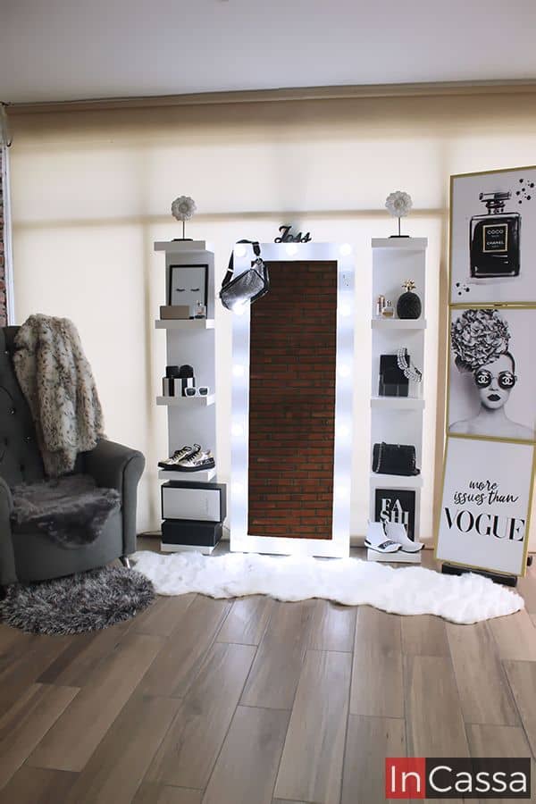 Una fotografía de una estación de tocador sofisticada en vibrante color blanco, con espejo de luces LED rodeado de estantes con repisas abiertas para exhibir accesorios y perfumes. Ideal para organizar en estilo.