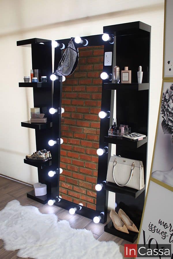 Este elegante tocador de pared en negro brillante, con luces LED alrededor del espejo, ofrece un diseño contemporáneo y funcional. Los estantes laterales negros con repisas exhiben productos de belleza y accesorios, aportando organización y estilo. Ideal para espacios modernos y sofisticados.