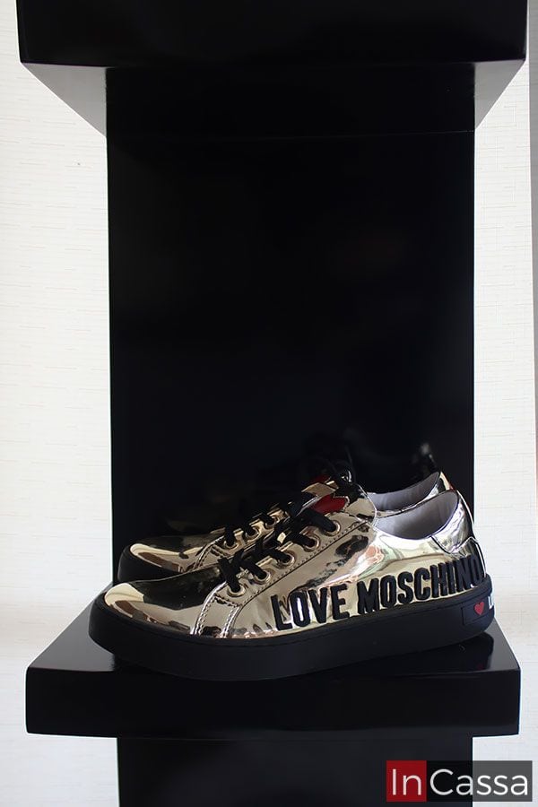 Se muestra en el estante de la estación de tocador negra, un par de zapatillas con diseño dorado brillante, añadiendo un toque de lujo y modernidad al espacio. Además de mostrar los múltiples usos que se le pueden dar a las repisas de los estantes laterales.