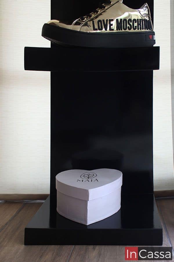 La imagen muestra la base de uno de los estantes negros decorada con una caja en forma de corazón, añadiendo un toque femenino y elegante. Este espacio es perfecto para organizar accesorios y detalles especiales en un entorno refinado.