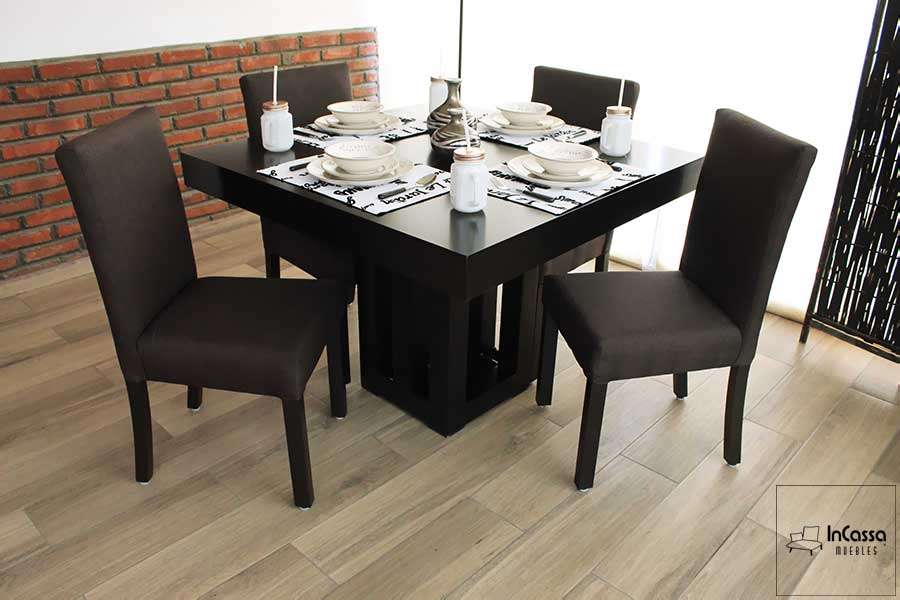 Una fotografía que presenta un comedor cuadrado para cuatro personas, compuesto por una mesa de líneas modernas en color chocolate y un pedestal central con diseño geométrico. Las sillas tapizadas en lino color chocolate complementan perfectamente el estilo contemporáneo del conjunto.