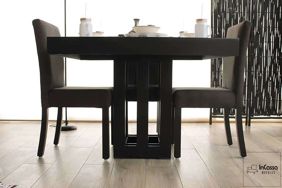 La fotografía muestra un ángulo bajo del comedor Brasil para cuatro personas, resaltando la moderna estructura de la base en acabado chocolate mate y las sillas tapizadas en lino en tono chocolate oscuro, todo en un ambiente contemporáneo y luminoso.