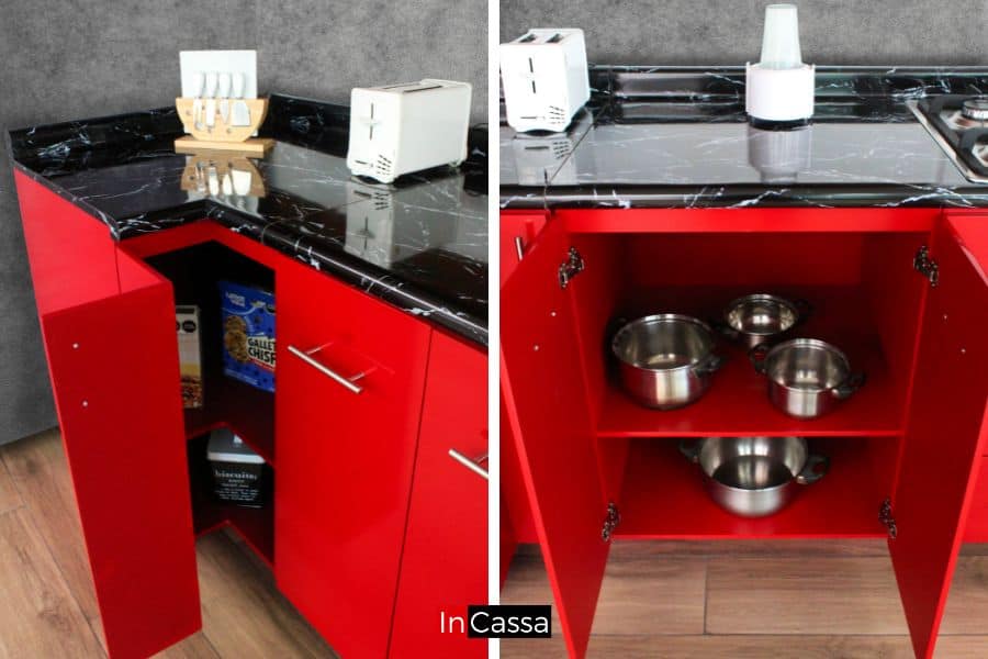 Se presentan los gabinetes inferiores de la cocina roja completa, destacando el diseño funcional para esquinas y almacenamiento espacioso. La cubierta de formaica negra con acabado marmoleado añade elegancia al vibrante color rojo, mientras que el interior optimiza el uso de cada espacio para utensilios y alimentos.