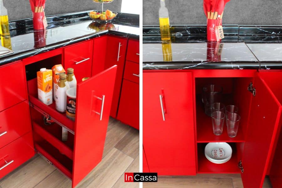 La imagen muestra módulos inferiores de la cocina en vibrante color rojo completo, en el que resalta un especiero oculto con espacios organizados para botellas y alimentos, así como almacenamiento para utensilios de mesa. El diseño combina funcionalidad y elegancia.
