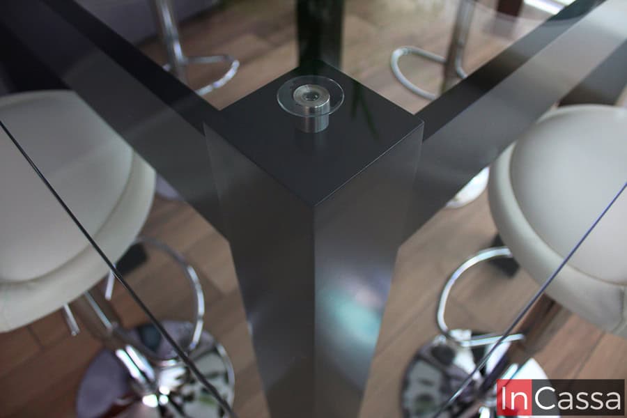 Una toma superior de la mesa del comedor chocolate, en la que se resalta la cubierta de cristal de la mesa, la cuál se encuentra en una posición suspendida gracias a separadores metálicos incorporados a la base de MDF Chileno de la mesa.