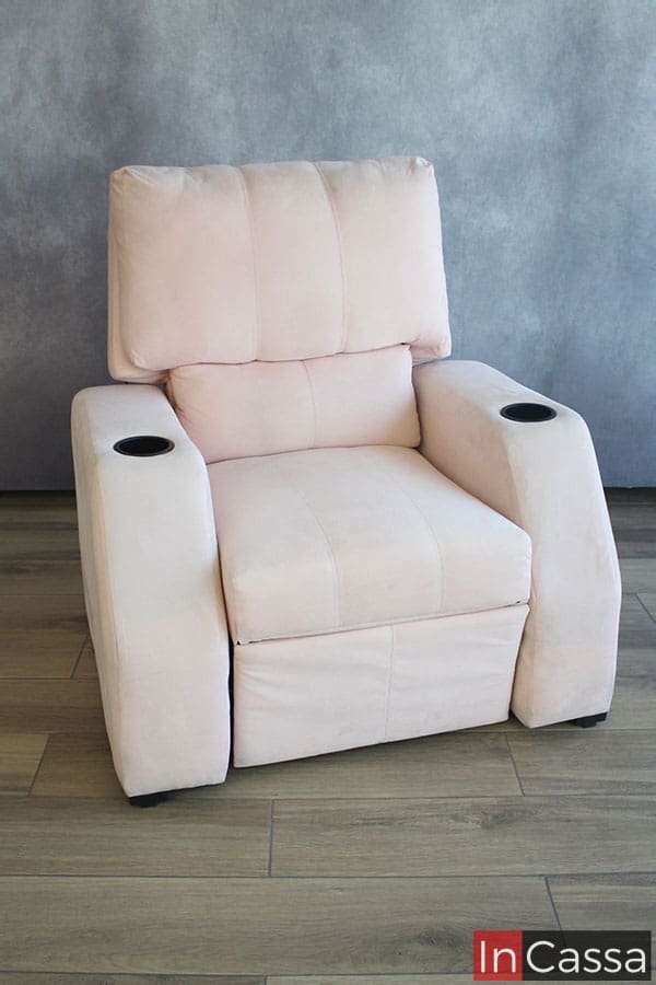 Vemos el sillón desde un ángulo frontal con el respaldo en su posición vertical, en la que tenemos una mejor vista de su asiento y de la estructura total del respaldo mismo. El reposet se presenta tapizado en suede rosa palo con porta vasos en los descansabrazos.