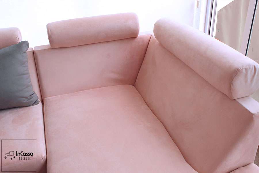 Vista lateral de la sala esquinera de suede rosa con reposacabezas cilíndricos ajustables. Diseño moderno y acogedor, perfecto para optimizar el confort en tu sala de estar con estilo y elegancia.