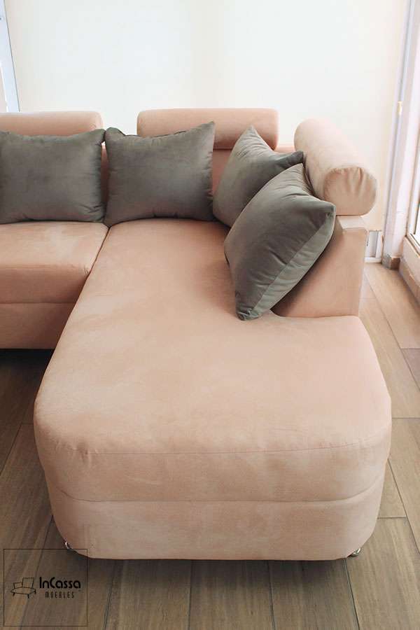 Sala esquinera tapizada en suede rosa con chaise long y cojines grises. Perfecto para ambientes modernos que buscan combinar comodidad y estilo en un solo mueble, creando un ambiente elegante y acogedor.