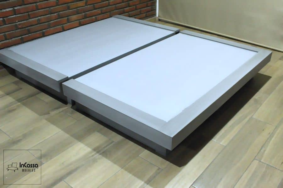 Se presenta un conjunto de dos módulos que conforman la base de cama en color gris cenizo claro con diseño de perfil bajo y bordes elevados. Su estructura modular permite configuraciones versátiles, ofreciendo estabilidad y un estilo contemporáneo ideal para espacios modernos.