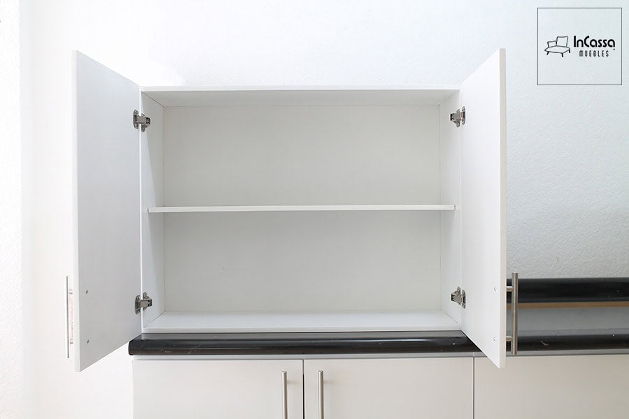 Esta imagen muestra un modulo superior en acabado blanco, con ambas puertas abiertas para exhibir su interior. El módulo cuenta con una repisa horizontal que divide el espacio en dos compartimentos amplios. Las bisagras metálicas internas y las jaladeras lineales cromadas añaden un toque moderno y funcional.