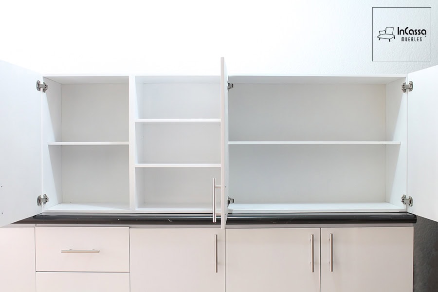 La imagen muestra la alacena superior en acabado blanco, vista de frente con puertas abiertas. La sección izquierda y derecha presentan dos amplios espacios divididos por repisas horizontales, ideales para almacenar vajilla o despensa. Al centro, una sección sin puertas incluye tres repisas fijas, perfectas para objetos decorativos o de uso frecuente. Todos los gabinetes están equipados con bisagras internas metálicas y jaladeras alargadas cromadas para un toque contemporáneo.