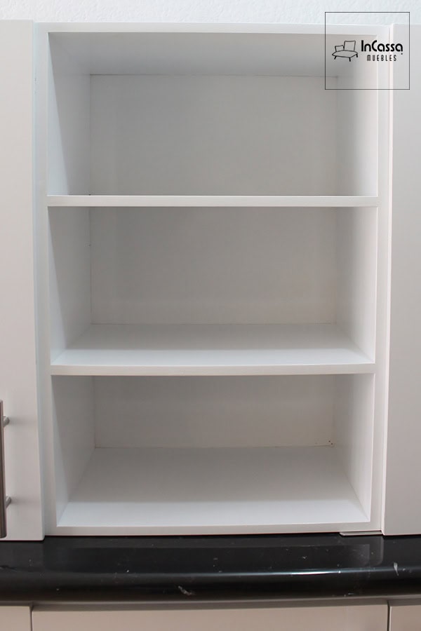 La foto muestra parte de la alacena superior en acabado blanco con diseño abierto y tres repisas fijas que forman cuatro compartimentos simétricos. Ideal para organizar frascos, tazas o elementos decorativos, este compartimento se integra armoniosamente con el resto de la cocina gracias a su estilo minimalista y limpio.