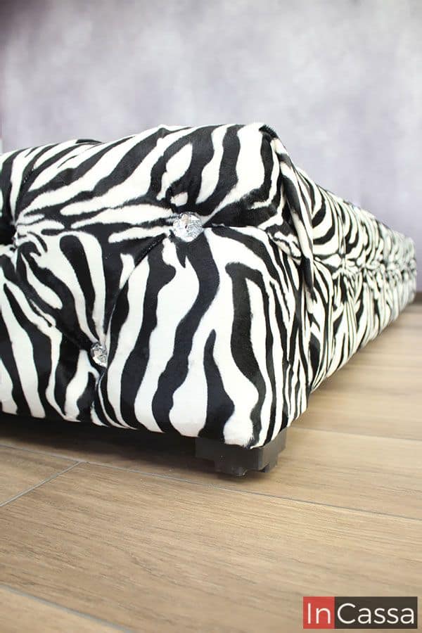 Esta toma destaca completamente el borde inferior de la base; en la que además de que se puede ver mejor la textura del tapiz lino cebra y los botones tipo diamante utilizados para el capitoneado, también se puede observar una de las patas de plástico café que sostienen la base.