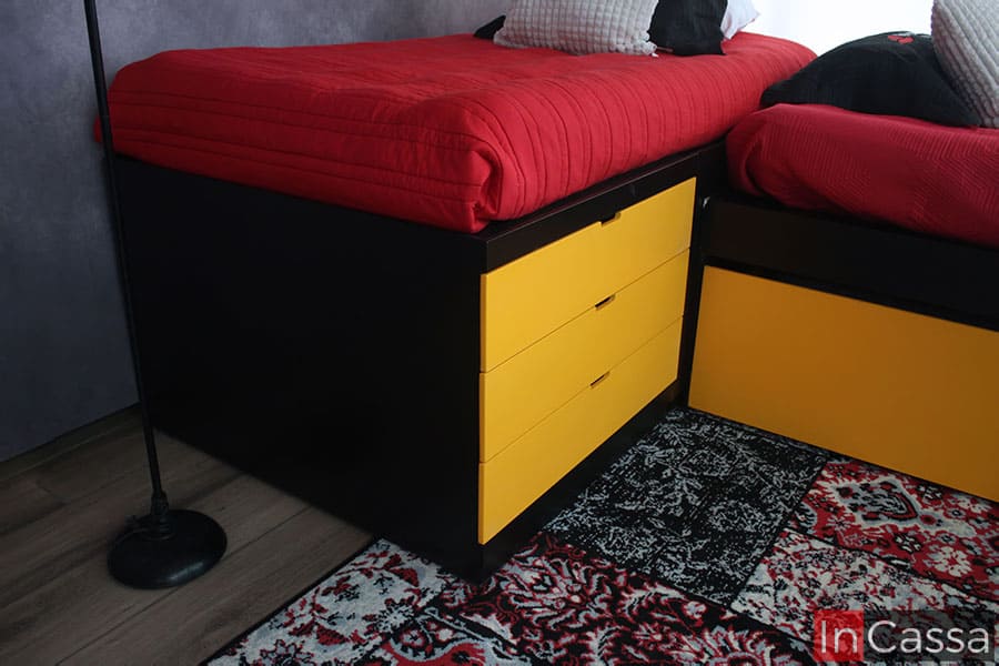 En esta foto se muestra un mayor enfoque en los tres cajones integrados a la base, cuyo diseño tiene un pequeño espacio en el borde superior de cada cajón el cuál funciona como jaladera. Los 3 cajones son de color amarillo, mientras que la toma también da un vistazo cercano a parte de la estructura de la base, la cuál es de color chocolate mate.