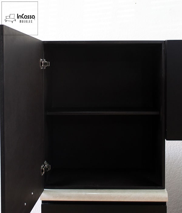 Se presenta una toma cercana de uno de los módulos superiores de la cocina Colombia en acabado chocolate mate. La imagen muestra el interior del gabinete con una repisa central que permite dividir el espacio en dos niveles para un mejor almacenamiento. Las bisagras metálicas aseguran un cierre firme y duradero.