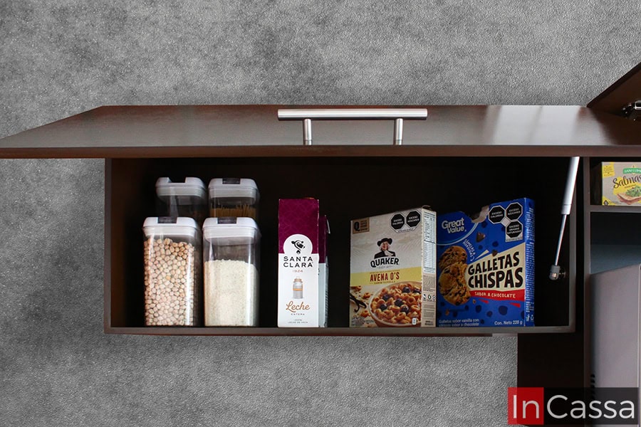 El mueble sobre campana de color tabaco completo cuenta con un compartimento amplio para almacenar productos secos y cereales. Sus puertas se abren hacia arriba con un mecanismo de pistón neumático, facilitando el acceso y manteniendo todo organizado.