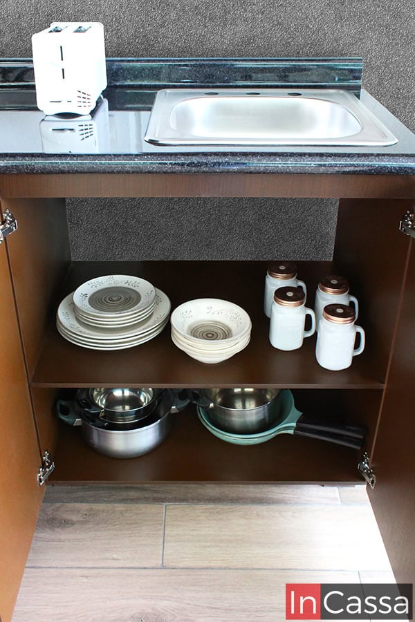 El módulo inferior de la cocina en color tabaco completo ofrece amplio almacenamiento debajo de la tarja, ideal para guardar vajillas, utensilios de cocina y ollas. Todo está organizado y fácilmente accesible.