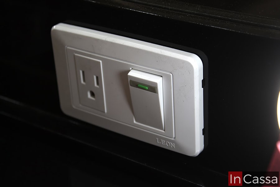 Una foto cercana del apagador integrado al espejo del tocador para encender y apagar sus 12 focos LED; el apagador incluye un enchufe para poder conectar secadoras y planchas para el cabello.