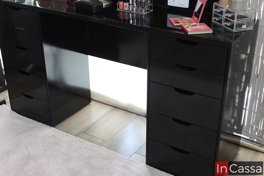 La foto se concentra en la mesa del tocador dando una vista más detallada del mueble, el cual esta pintado completamente en color negro brillante. El mueble cuenta con un total de diez cajones (cinco por lado).