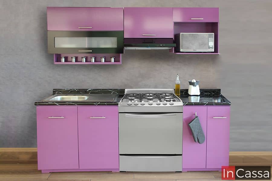 Cocina integral moderna en color uva, ideal para optimizar espacios. Incluye alacenas superiores, espacio para microondas, tarja de acero inoxidable, y gabinetes inferiores con cubierta de formaica estilo mármol negro.