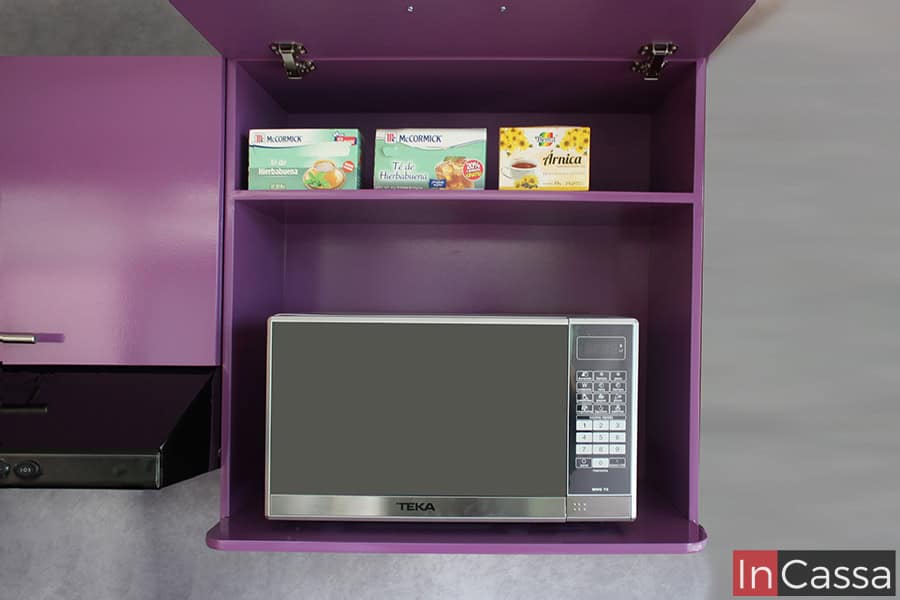 Una fotografía del gabinete superior en color uva completo, diseñado específicamente para almacenar un microondas. El compartimento superior aloja cajas de té y otros productos, mostrando la versatilidad del espacio para mantener la cocina organizada y funcional.